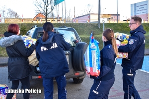 Policjanci wraz z wolontariuszką idą spakować rzeczy ze zbiórki do pojazdu