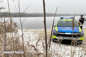 Policyjny radiowóz, w tle widoczne jezioro