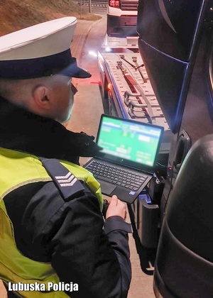 Policjant drogówki podczas przeprowadzania kontroli drogowej z wykorzystanie laptopa.