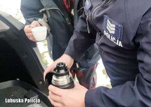 policjant nalewa herbaty dla bezdomnego