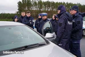 Policjanci stojący przy pojeździe osobowym.