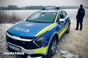 radiowóz i policjant stoją przy zamarzniętym jeziorze