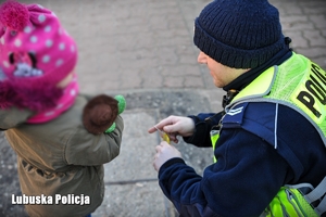 policjant wręcza dziecku odblask