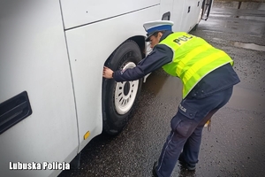 policjantka sprawdza stan ogumienia autokaru