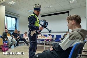 Policjant ruchu drogowego pokazuje urządzenie do pomiaru prędkości