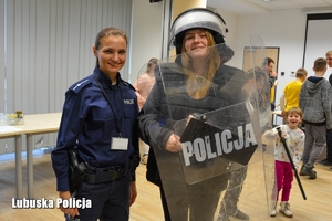 Policjantka wraz z dziewczyną, która trzyma tarcze