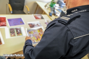policjant przegląda prace plastyczne