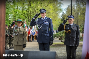 policjant i przedstawiciele służb oddają honor do Krzyża Katyńskiego