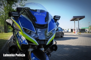 Motocykl policyjny w tle widoczny samochod osobowy