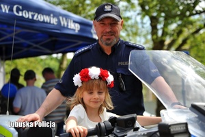dziewczynka siedzi na motocyklu obok policjanta