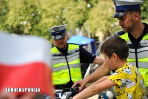 policjanci pokazują chłopcu motocykl