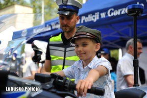 dziecko siedzi na motocyklu obok policjanta