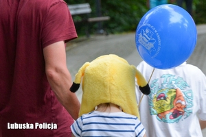 Dziecko w żółtej czapce z balonem w ręce