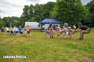 Dzieci wraz z policjantem przeciągają linę