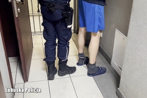 policjant stoi przy zatrzymanym mężczyźnie