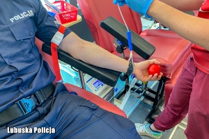 policjant w krwiobusie przygotowuje się do oddania krwi