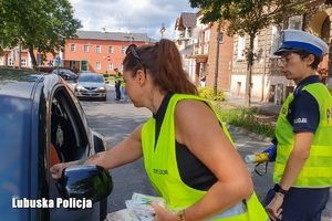 Kobieta z policjantką rozdają broszury informacyjne