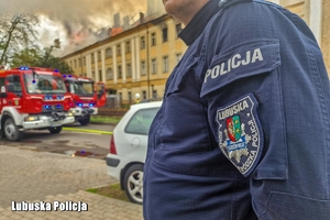 Policjant zabezpieczający miejsce zdarzenia podczas akcji gaśniczej strażaków