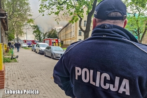 Policjant zabezpieczający miejsce zdarzenia podczas akcji gaśniczej strażaków