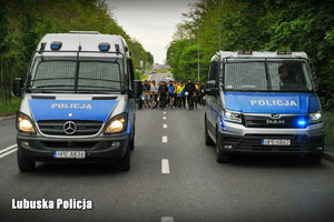 Za radiowozami policjanci prowadzą kibiców