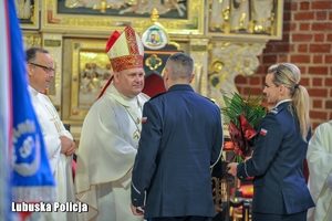 Policjanci wręczają duchownemu kwiaty