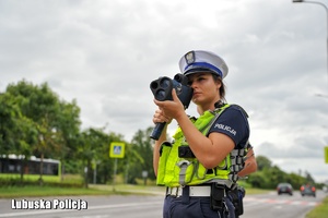 Policjantka ruchu drogowego mierzy prędkość pojazdów