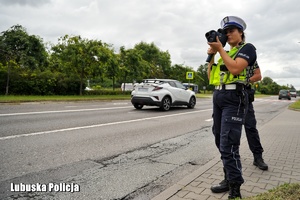 Policjantka ruchu drogowego mierzy prędkość pojazdów
