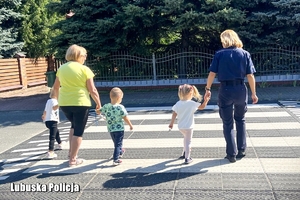 Policjantka bezpiecznie prowadzi dzieci przez ulicę