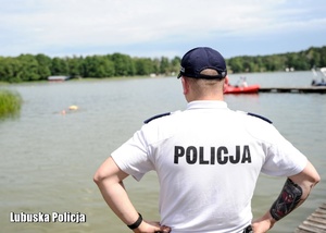 Policjant stojący nad jeziorem.