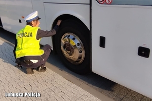 policjantka kontroluje stan ogumienia autokaru