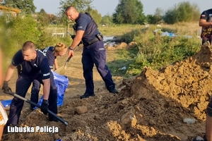 policjanci pomagają ładować worki z piaskiem