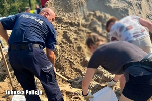 Policjanci pomagają przy zabezpieczeniu przed powodzią