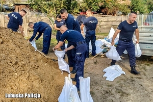 policjanci pomagają szykować worki z piaskiem