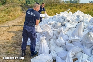 policjanci pomagają szykować worki z piaskiem