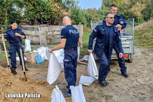 policjanci pomagają szykować worki z piaskiem