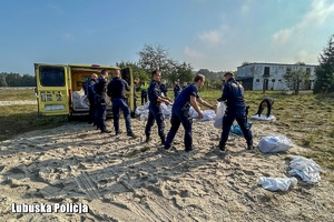 policjanci pomagają szykować worki z piaskiem