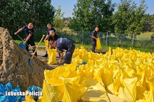 Policjanci przygotowują worki do zabezpieczenia wału