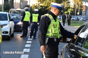 Policjant ruchu drogowego stojący przy samochodzie osobowych