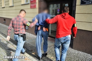 Policjanci służby kryminalnej prowadzą zatrzymanego