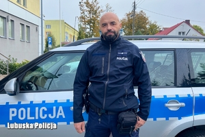 Policjant na tle radiowozu