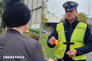 policjant przekazuje osobie odblask