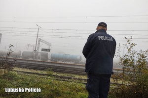 Policjant patrzy w kierunku stacji kolejowej