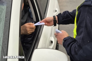 Policjant wręcza plakietkę profilaktyczną