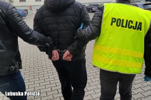 Policjant eskortuje podejrzanego