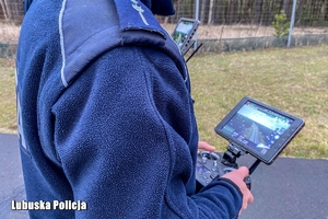 policjant trzyma urządzenie sterujące dronem