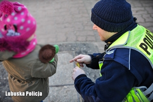 Policjant przekazuje odblask dziecku