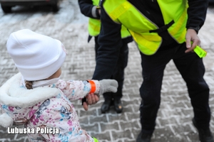 Policjant przekazuje odblask dziecku