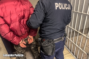 policjant prowadzi zatrzymaną osobę