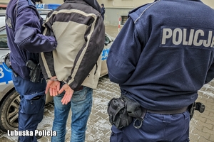 policjanci prowadzą zatrzymaną osobę