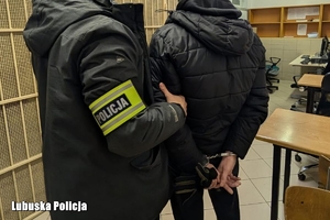 policjant prowadzi zatrzymaną osobę